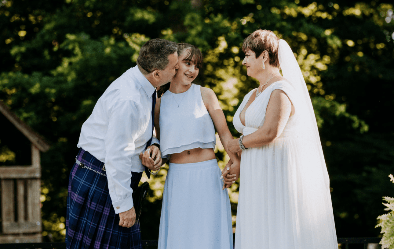 groom gives his stepdaughter a smooch during the wedding ceremony as he marries her mom. Images by Kristyn Miller