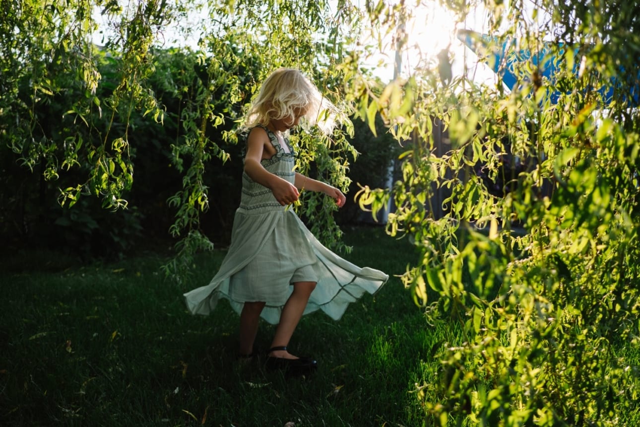 little blonde four year old girl spins her dress in this backyard photo session with Kristyn Miller Photography framed by a willow tree and the soft afternoon light